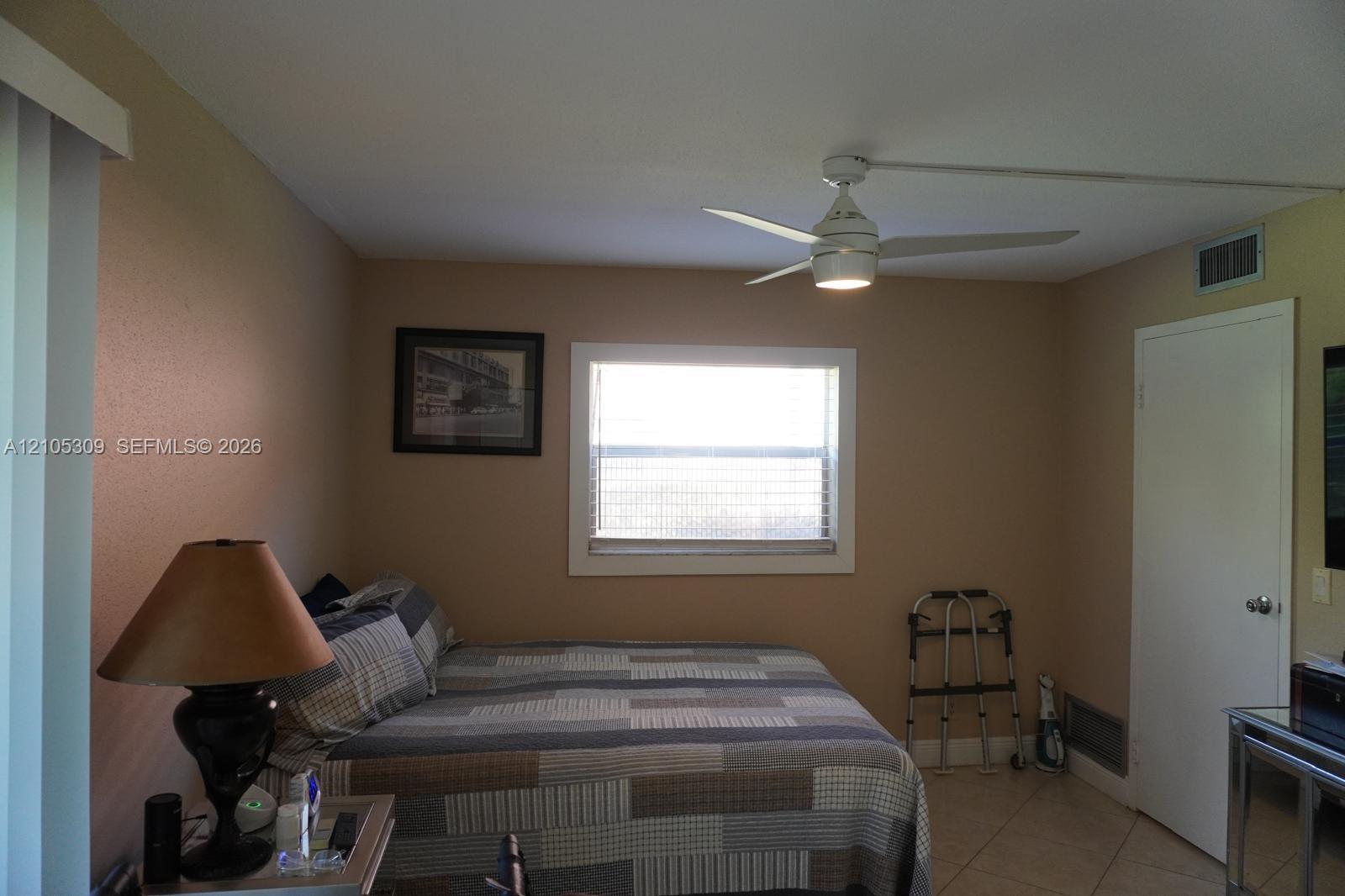 Room featuring a central window, white ceiling fan with integrated lighting, neutral wall paint, and tile flooring Room featuring a central window, white ceiling fan with integrated lighting, neutral wall paint, and tile flooring