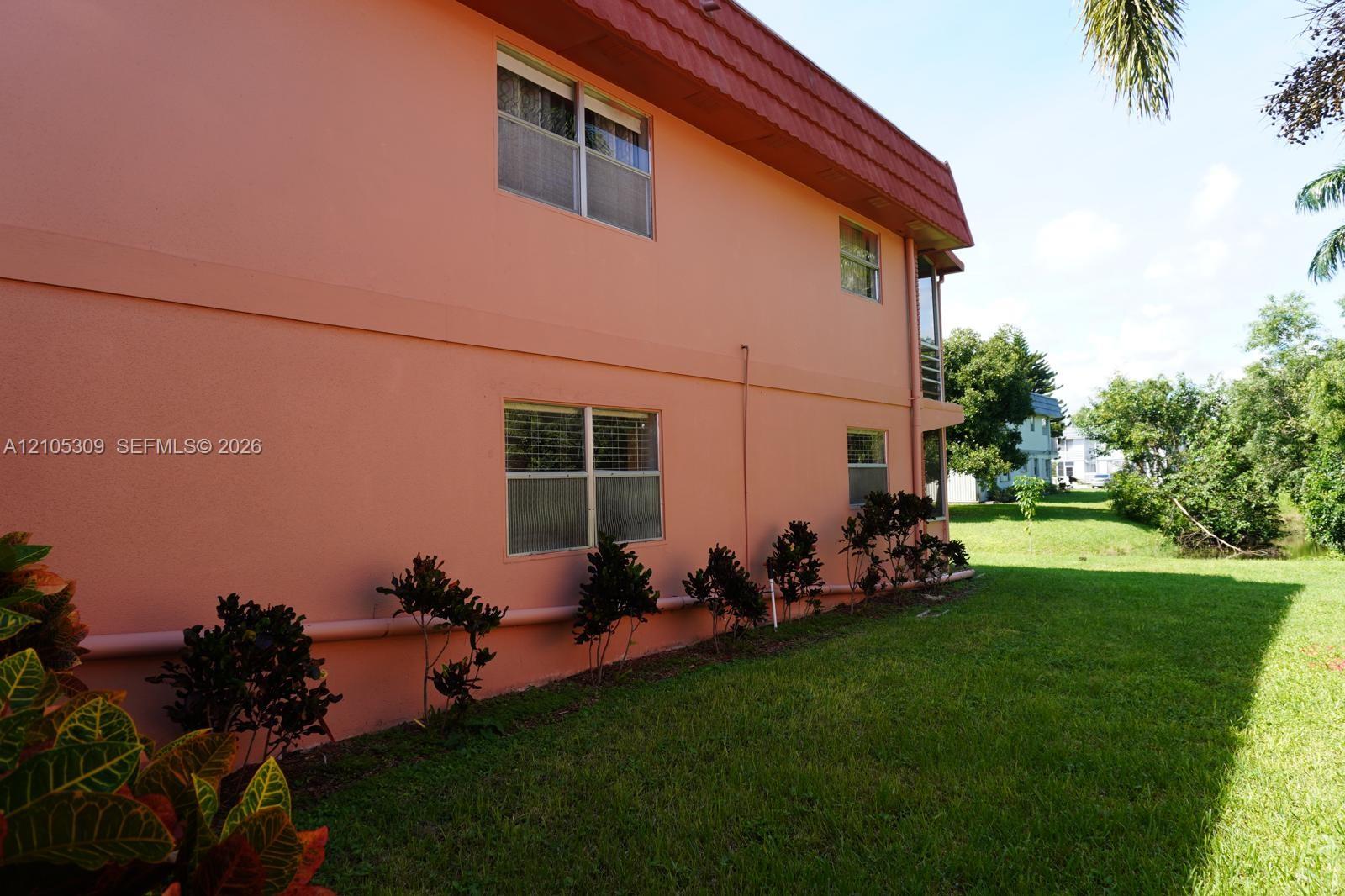 Two-story exterior featuring smooth stucco siding, a mansard roofline, multi-pane windows, and manicured perimeter landscaping Two-story exterior featuring smooth stucco siding, a mansard roofline, multi-pane windows, and manicured perimeter landscaping