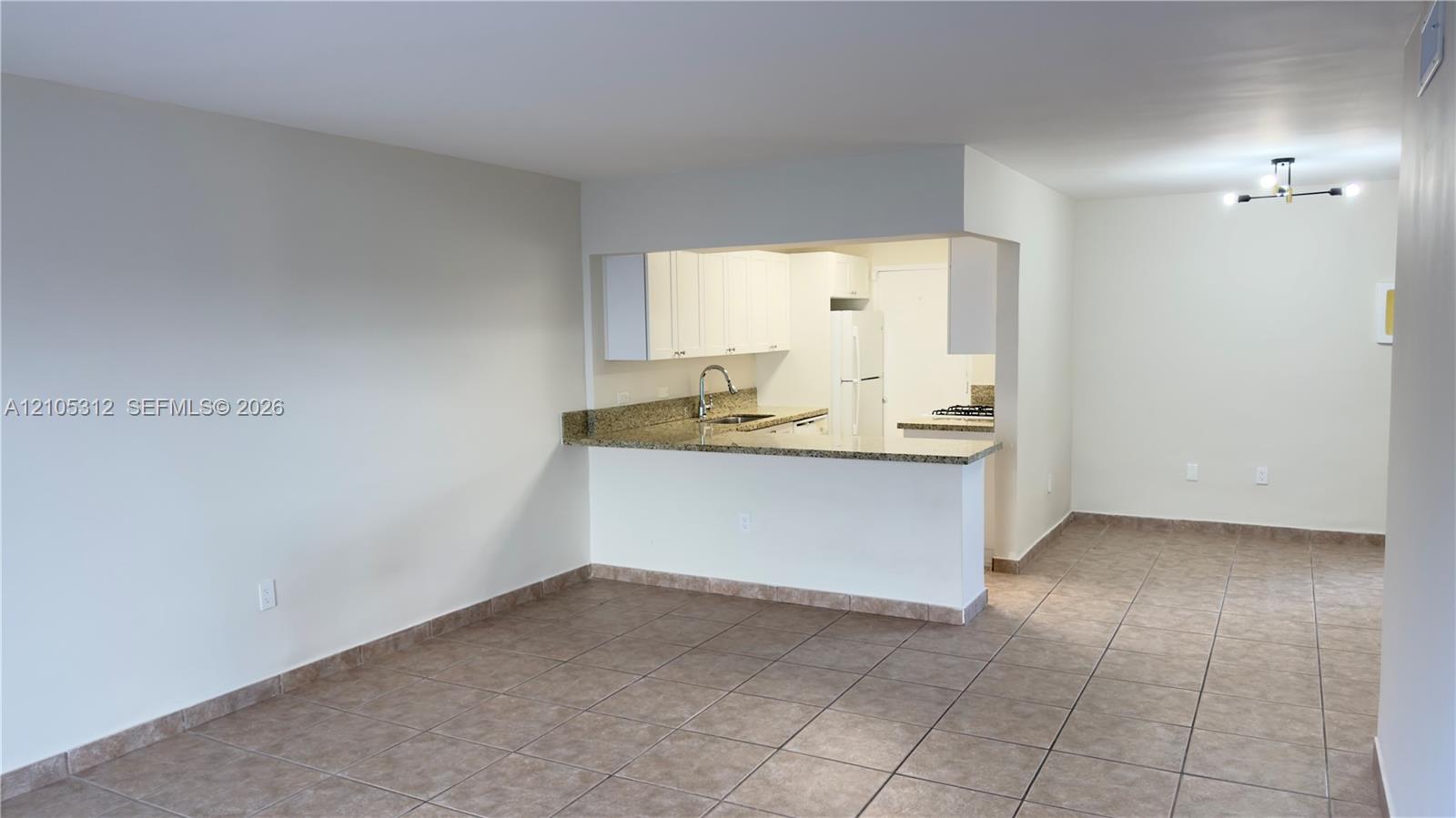 Kitchen featuring stone-finish countertops, white cabinetry, tile flooring, a dual-basin sink with a gooseneck faucet, and a multi-light flush-mount fixture