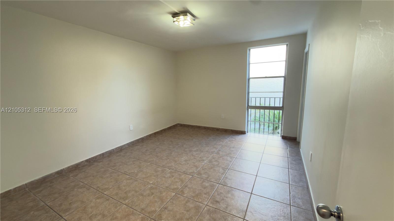 Room featuring neutral wall finishes, tile flooring, a large window, and an overhead lighting fixture