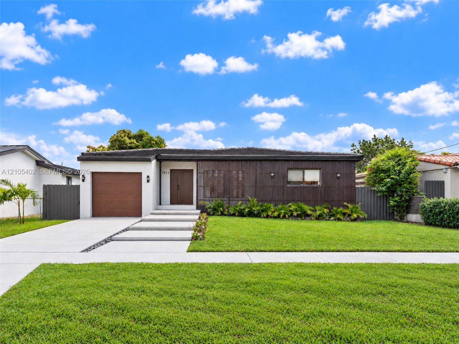 Contemporary single-story exterior featuring dark wood-tone vertical siding, a concrete paver walkway, an integrated single-car garage, and a manicured front lawn Contemporary single-story exterior featuring dark wood-tone vertical siding, a concrete paver walkway, an integrated single-car garage, and a manicured front lawn
