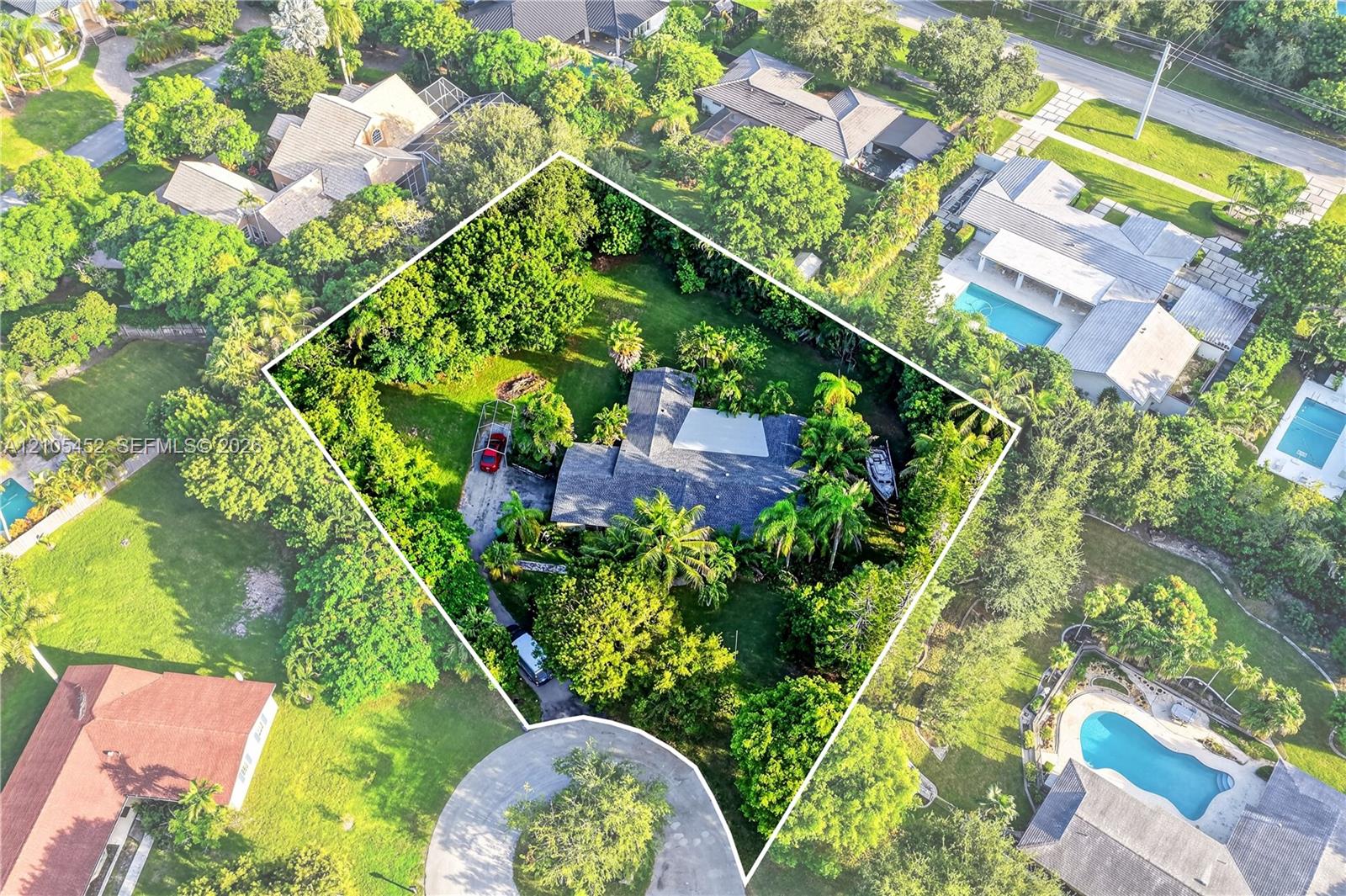 Aerial perspective of a sprawling property featuring mature canopy trees, expansive lawn space, and a multi-section roofline