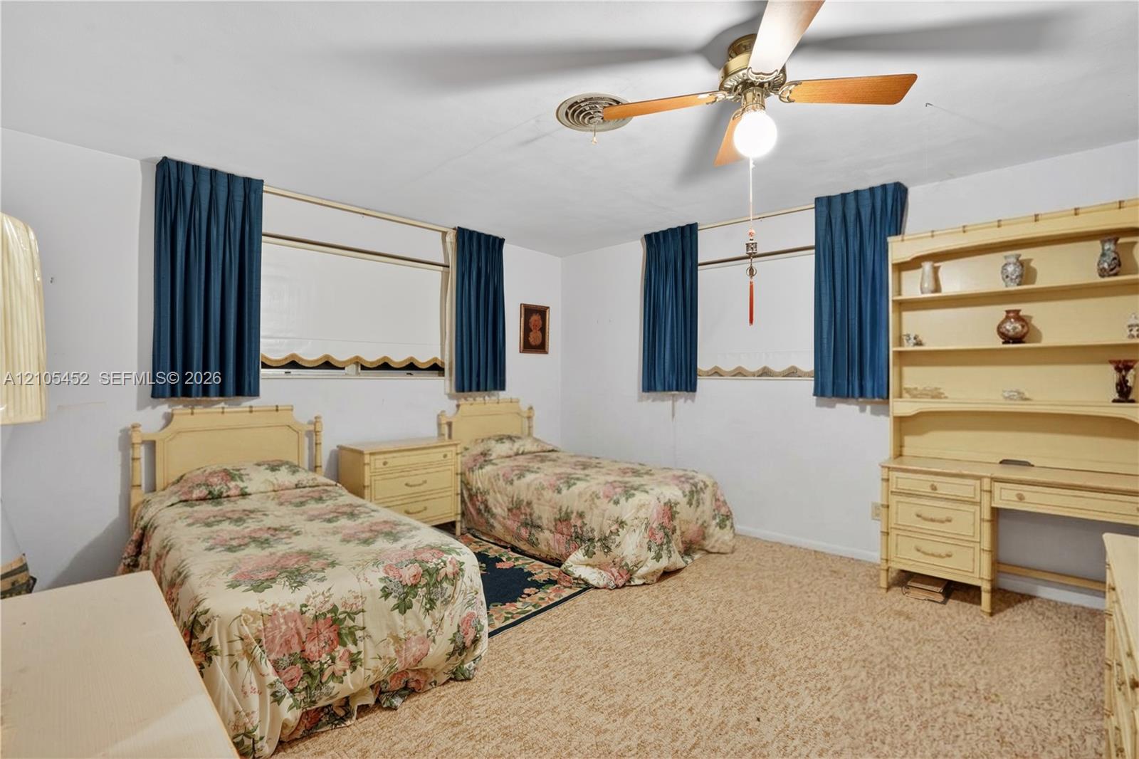 Built-in wall cabinetry with shelving and integrated desk, textile flooring, and ceiling fan with light fixture
