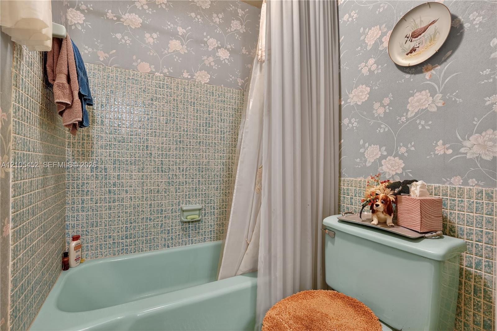 Bathroom featuring floral-patterned wall coverings, mosaic tile surround, and a built-in soap dish