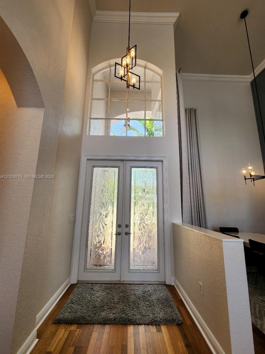 Double entry doors with patterned glass, hardwood flooring, and a modern hanging light fixture