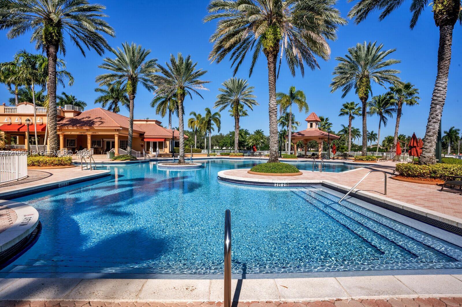 Swimming pool featuring a sun shelf, paved pool deck, tiled water line, built-in steps, and handrails