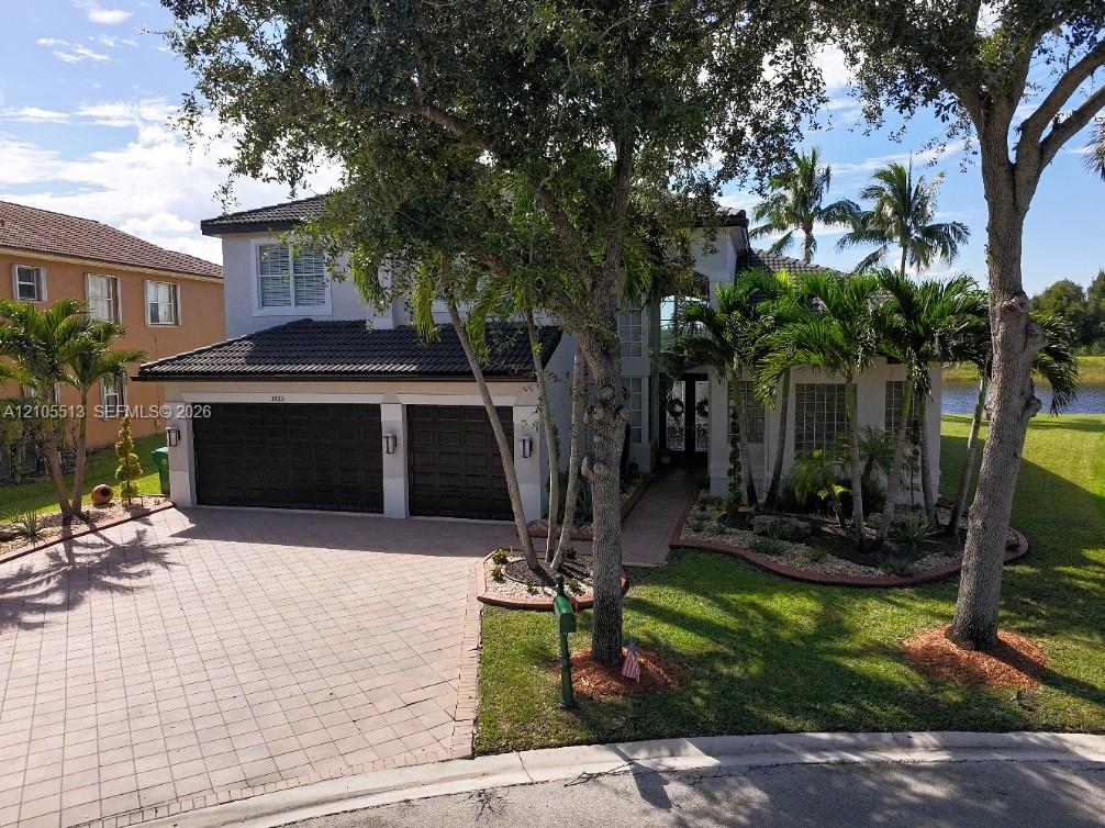 Two-story residence with a paved 6-car driveway, 3-car garage, and mature landscaping