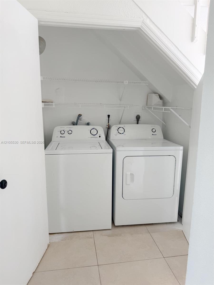 Laundry area featuring a washer and dryer, tile flooring, and integrated shelving