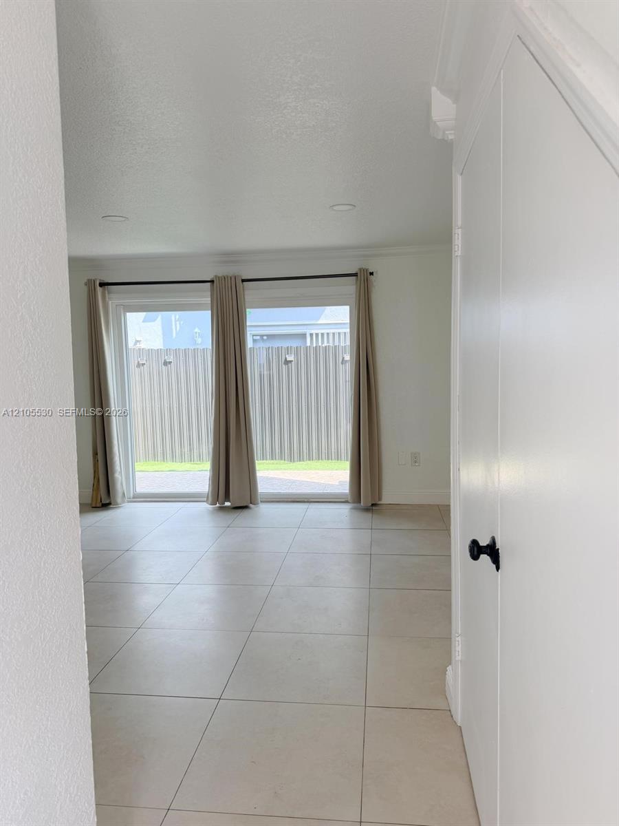 Sliding glass doors, recessed ceiling lighting, tile flooring, and crisp white trim