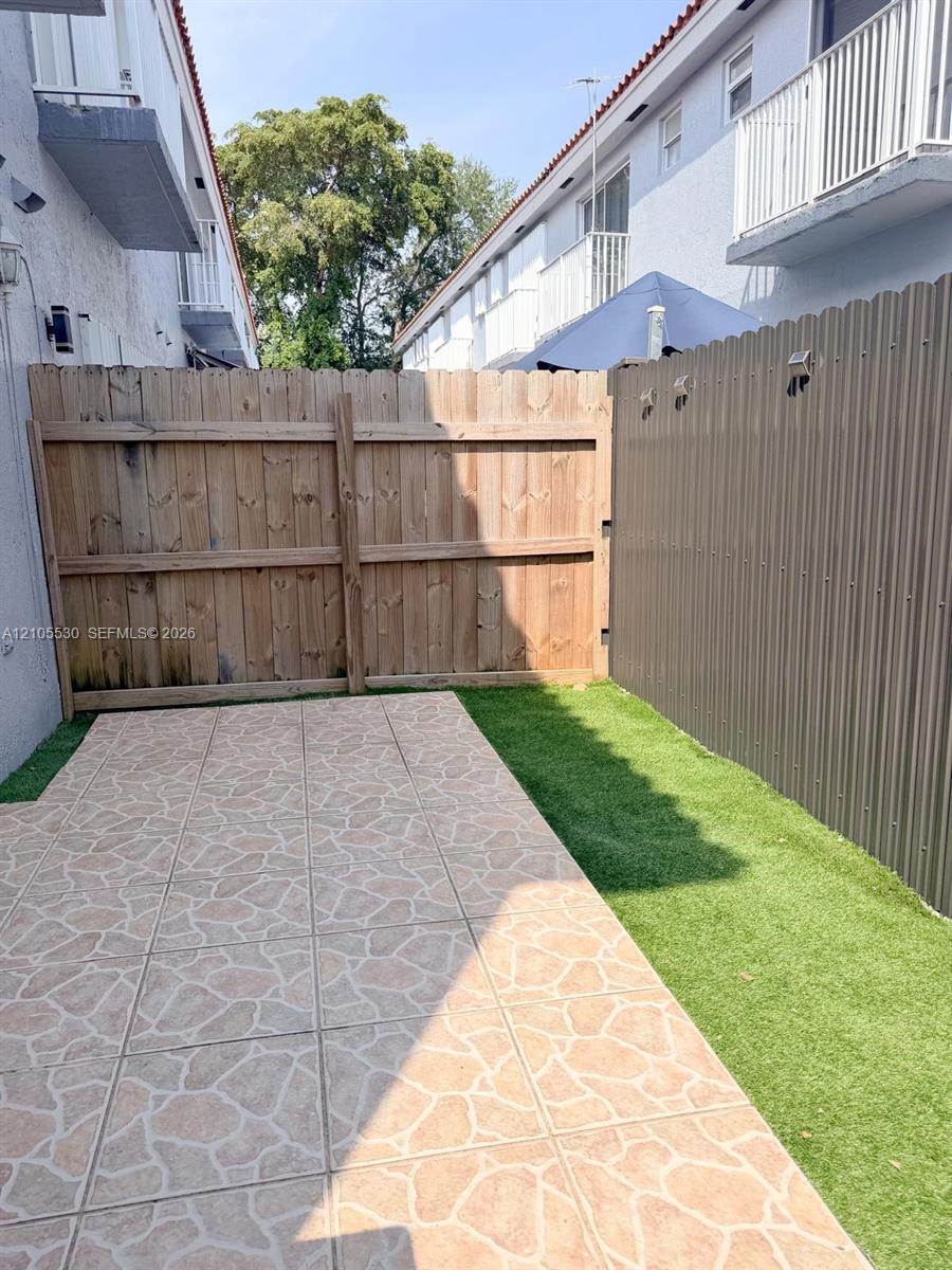 Private outdoor patio featuring tiled flooring and artificial turf