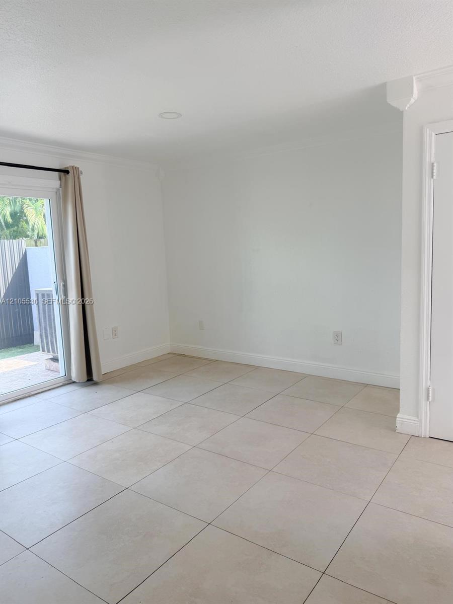 Recessed lighting, crown molding, white walls, light-toned tile flooring, and a sliding glass door