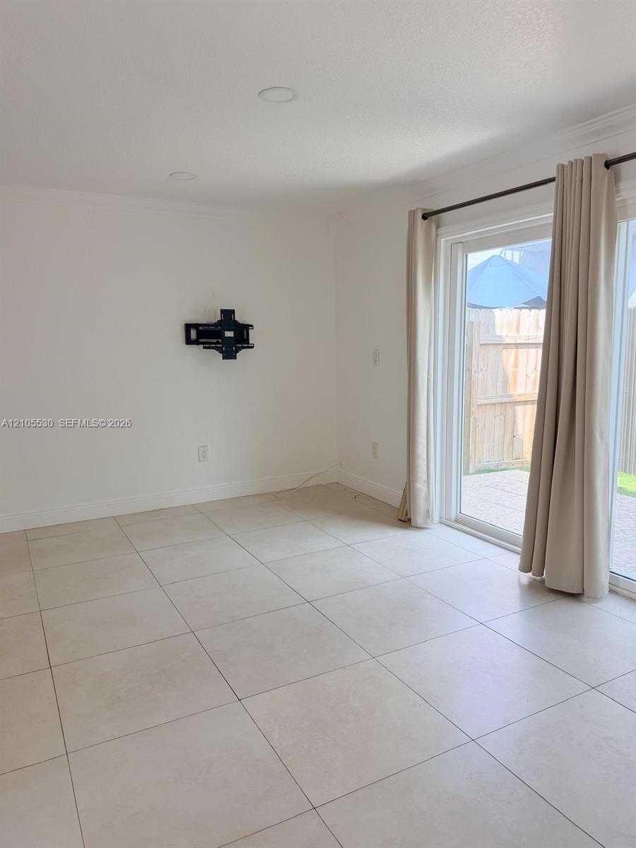 Recessed lighting, light-toned tile flooring, and sliding glass doors to exterior
