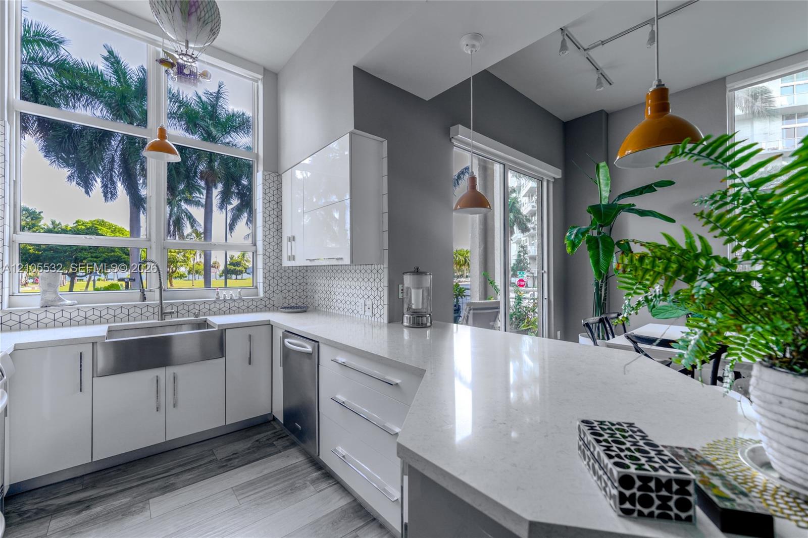 Kitchen featuring white high-gloss cabinetry, quartz countertops, a stainless steel farmhouse sink, geometric tile backsplash, and wood-finish flooring