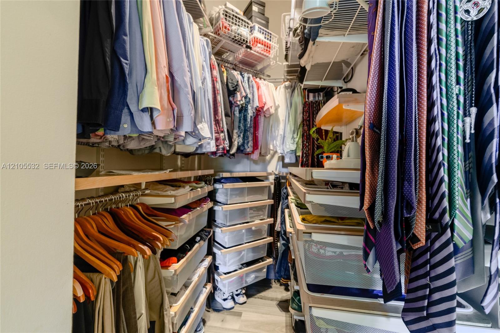 Walk-in closet featuring multi-tiered hanging rods, integrated pull-out drawer organizers, overhead shelving, and neutral flooring