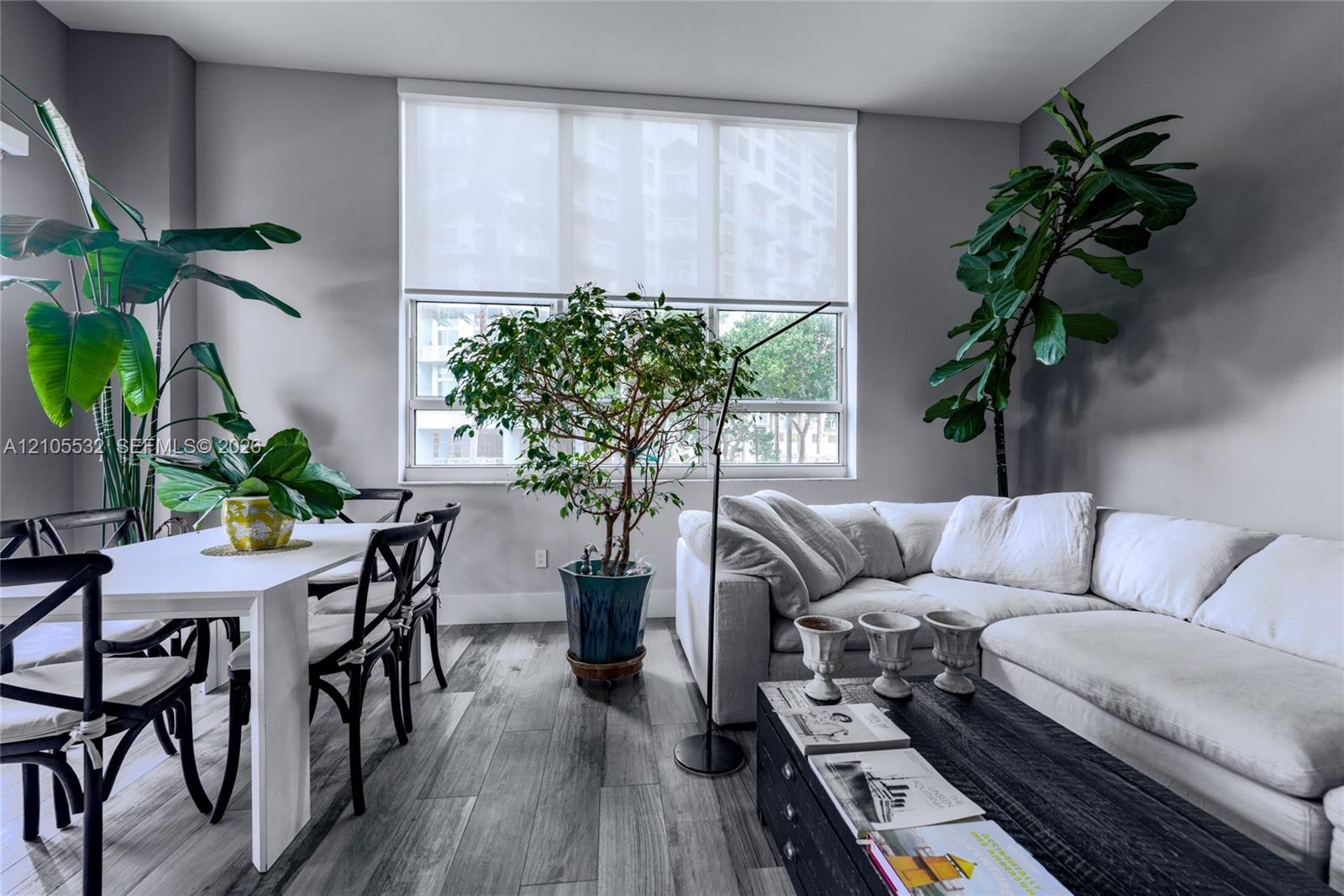 Living space featuring wood-finish flooring and a large multi-pane window with a neutral roller shade