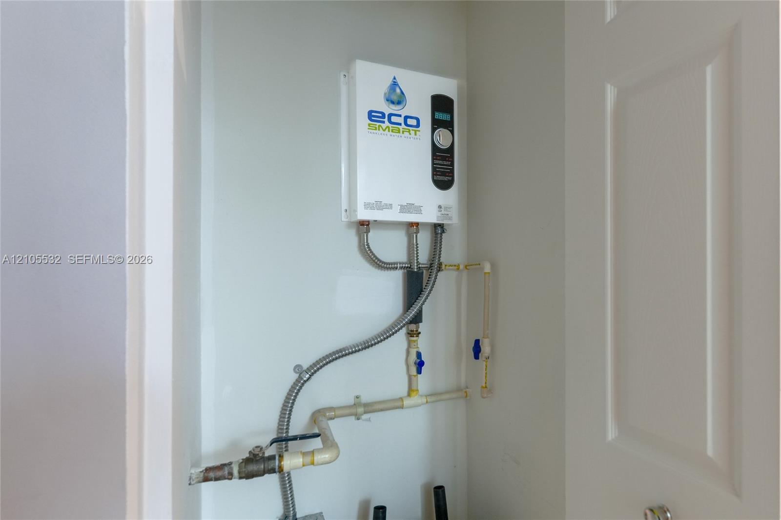 Tankless electric water heating system featuring a digital temperature control interface and integrated plumbing connections