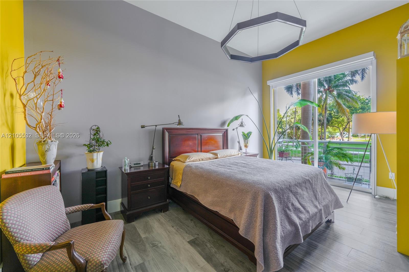 Wood-finish flooring, high ceilings, large sliding glass door with balcony access, and a geometric pendant light fixture