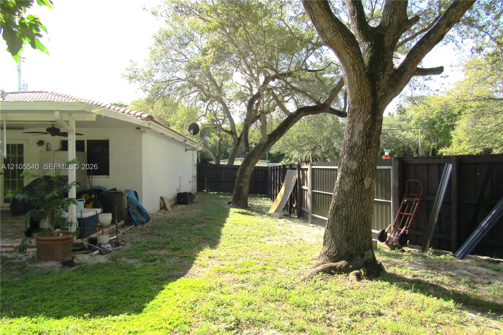 Expansive lawn area featuring mature trees and a privacy fence