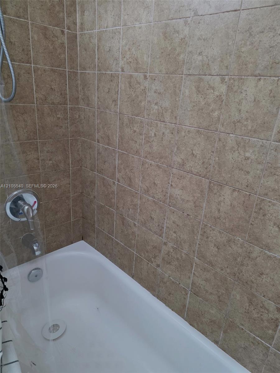 White bathtub with chrome fixtures and tiled surround