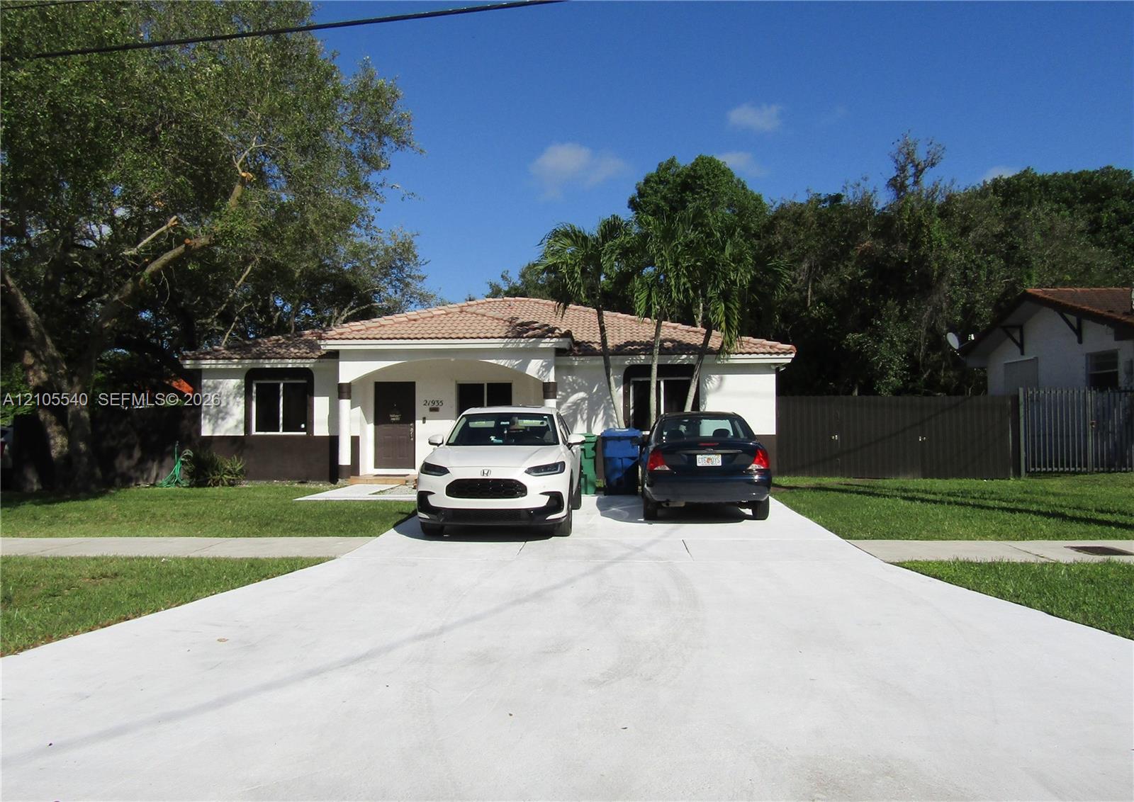 Exterior with a tile roof, covered entry, and a concrete driveway