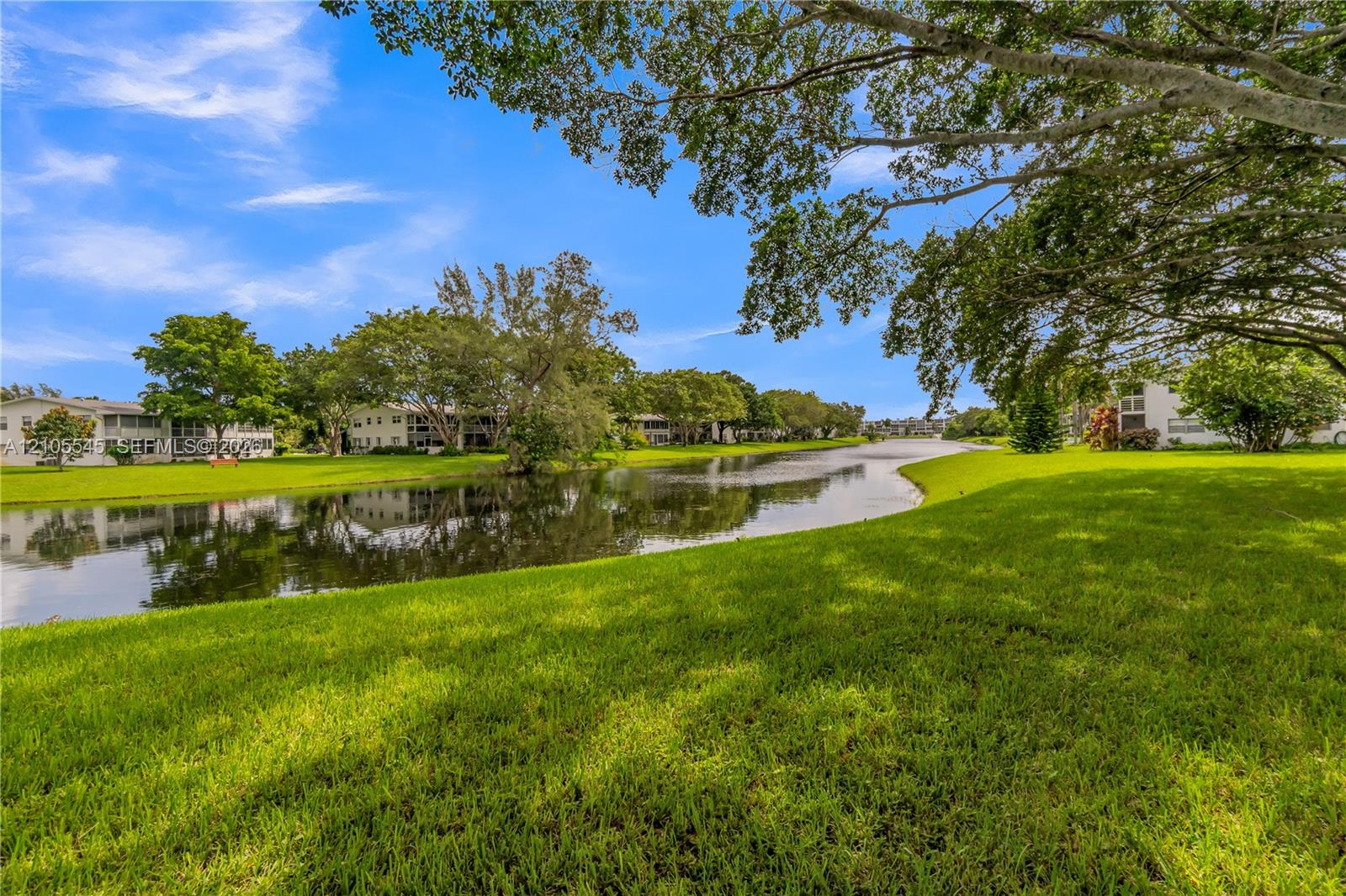 Expansive green space with manicured lawn, mature trees, and a tranquil water feature Expansive green space with manicured lawn, mature trees, and a tranquil water feature
