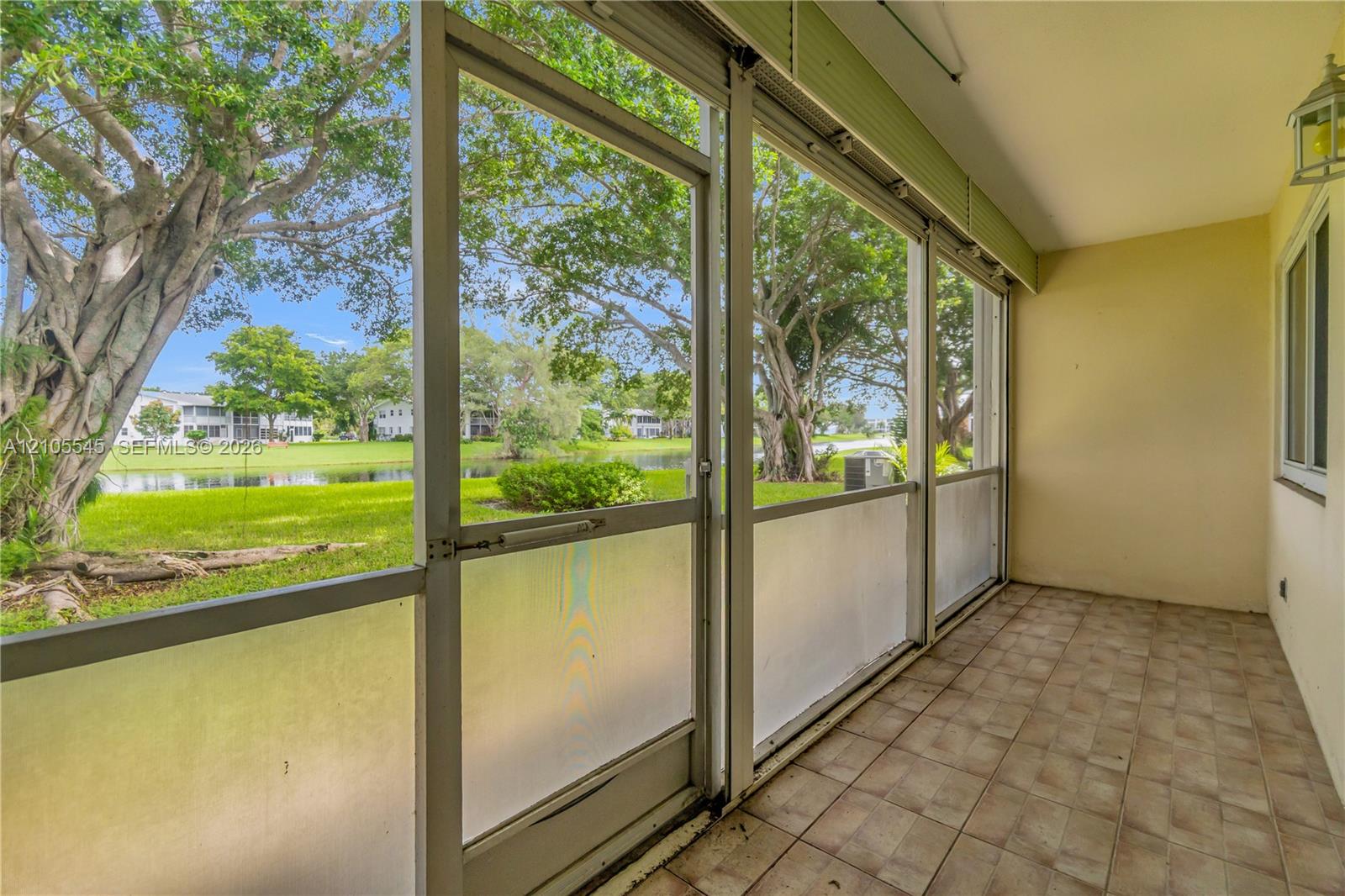 Screened patio with tiled flooring, featuring a wall-mounted lantern light fixture