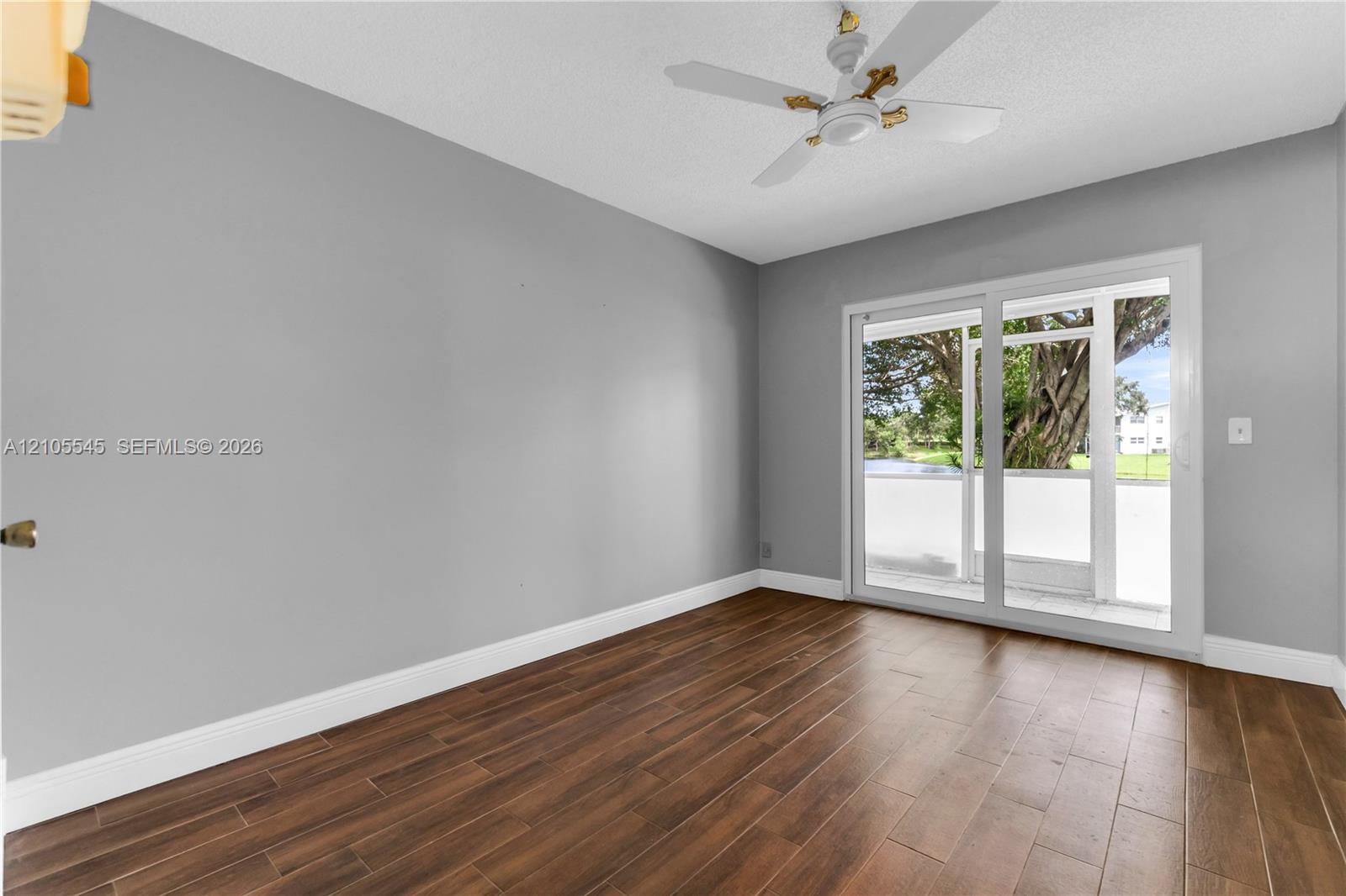 Wood-finish ceramic flooring with light gray walls, white baseboards, and a ceiling fan
