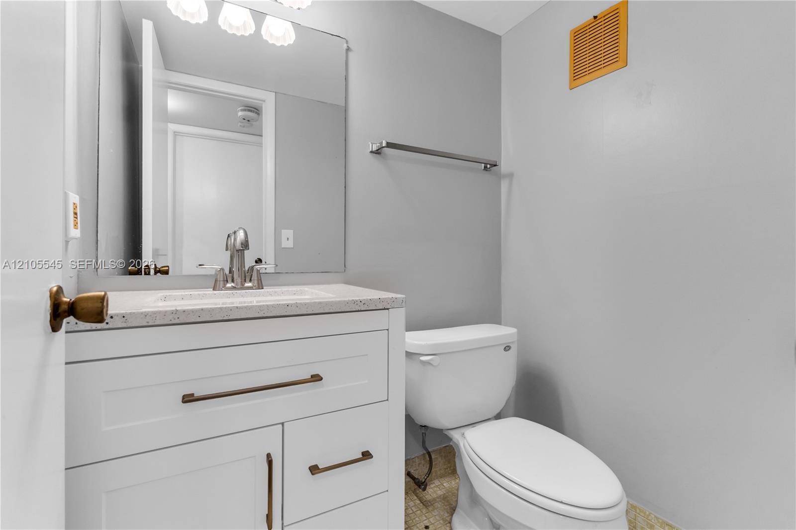 White vanity with bronze hardware, a white countertop, and a chrome faucet