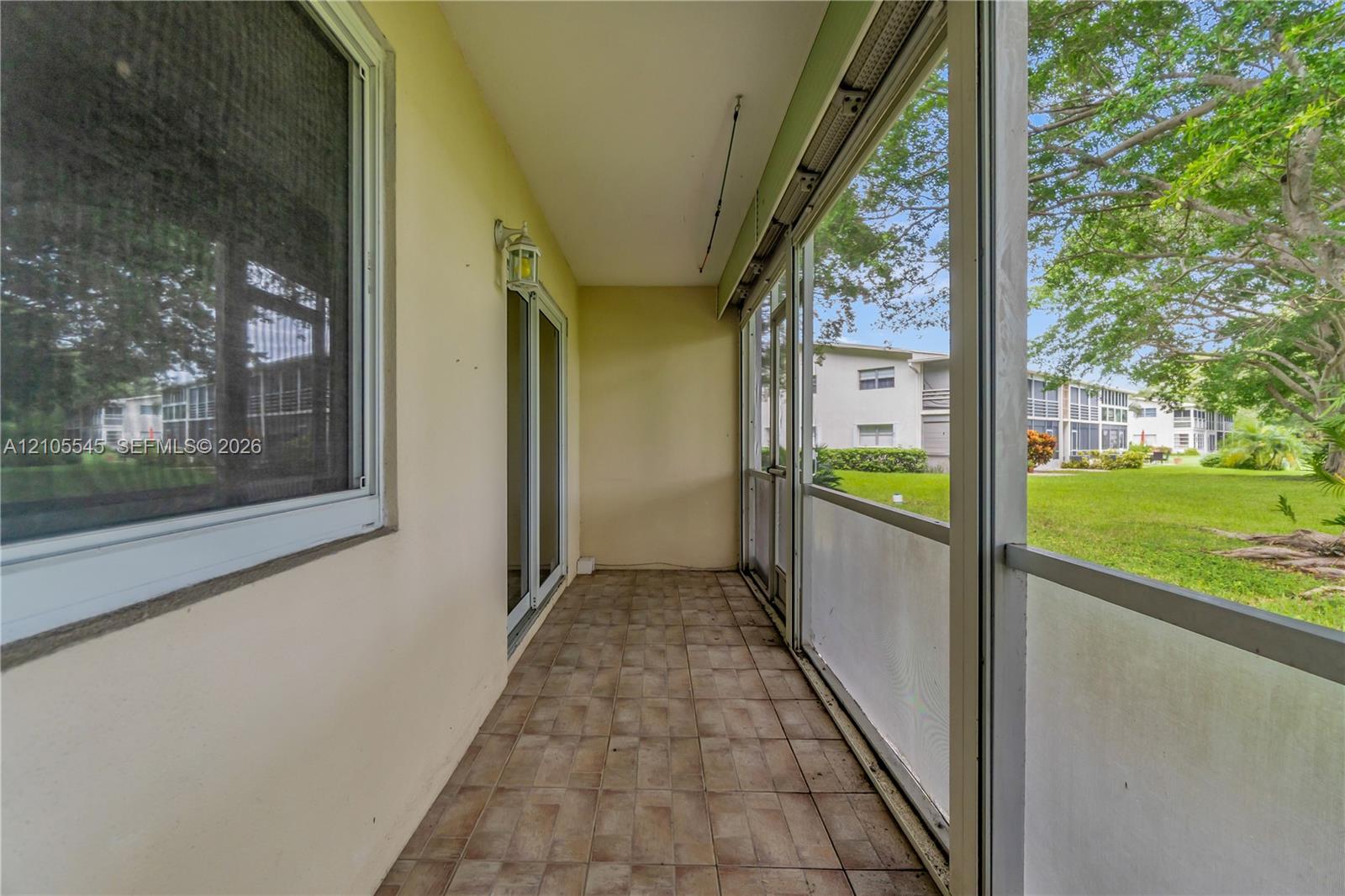 Screened patio with tiled flooring and exterior lighting fixture