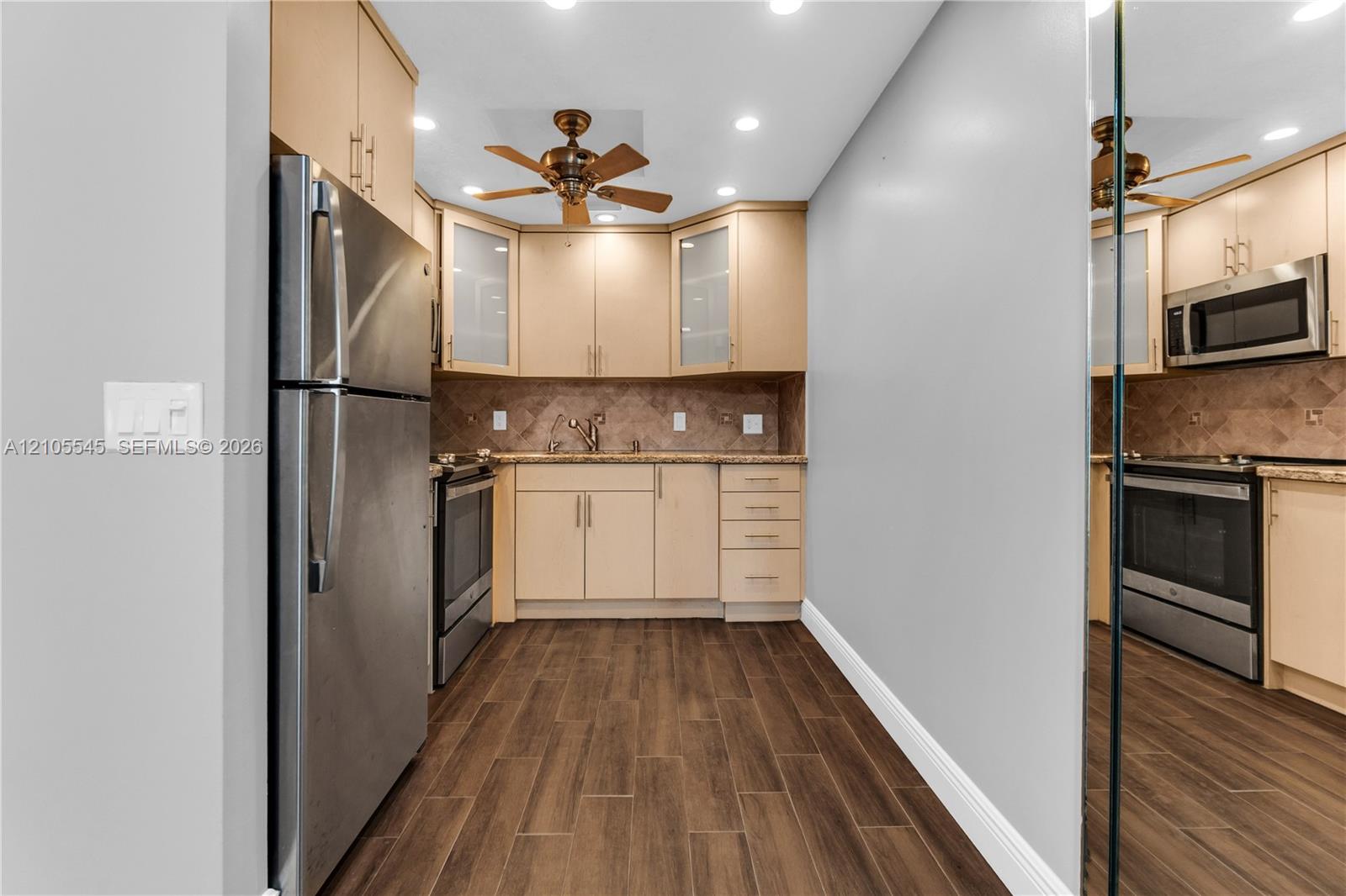 Kitchen featuring stainless steel appliances, wood-finish flooring, recessed lighting, a ceiling fan, and ample cabinetry