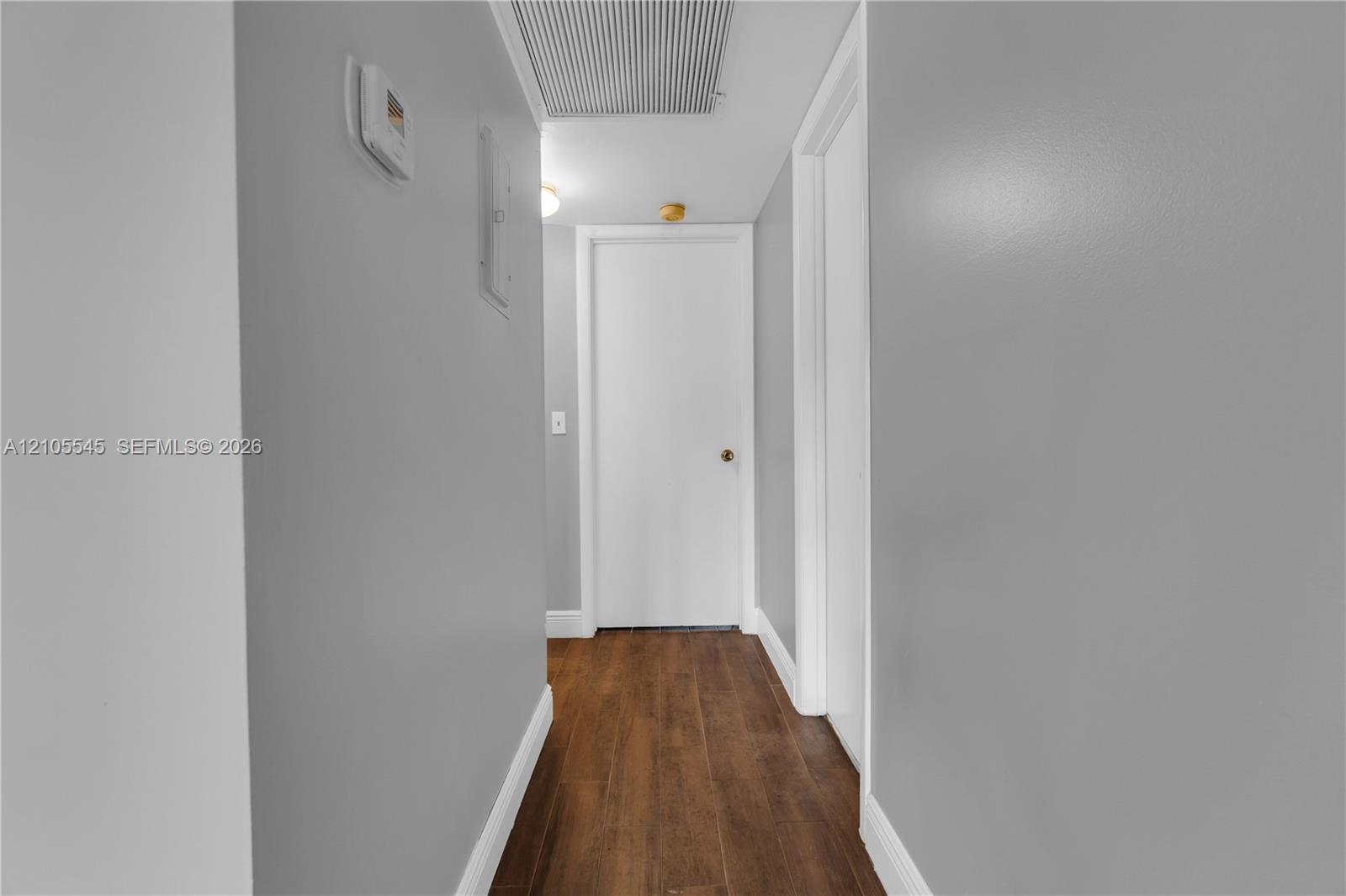 Hallway with wood-finish ceramic flooring, light gray wall paint, and white trim