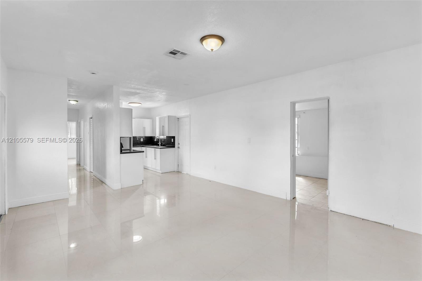 Interior space featuring neutral wall tones, large-format tile flooring, recessed and flush-mount ceiling lighting, and kitchen cabinetry with contrasting countertops