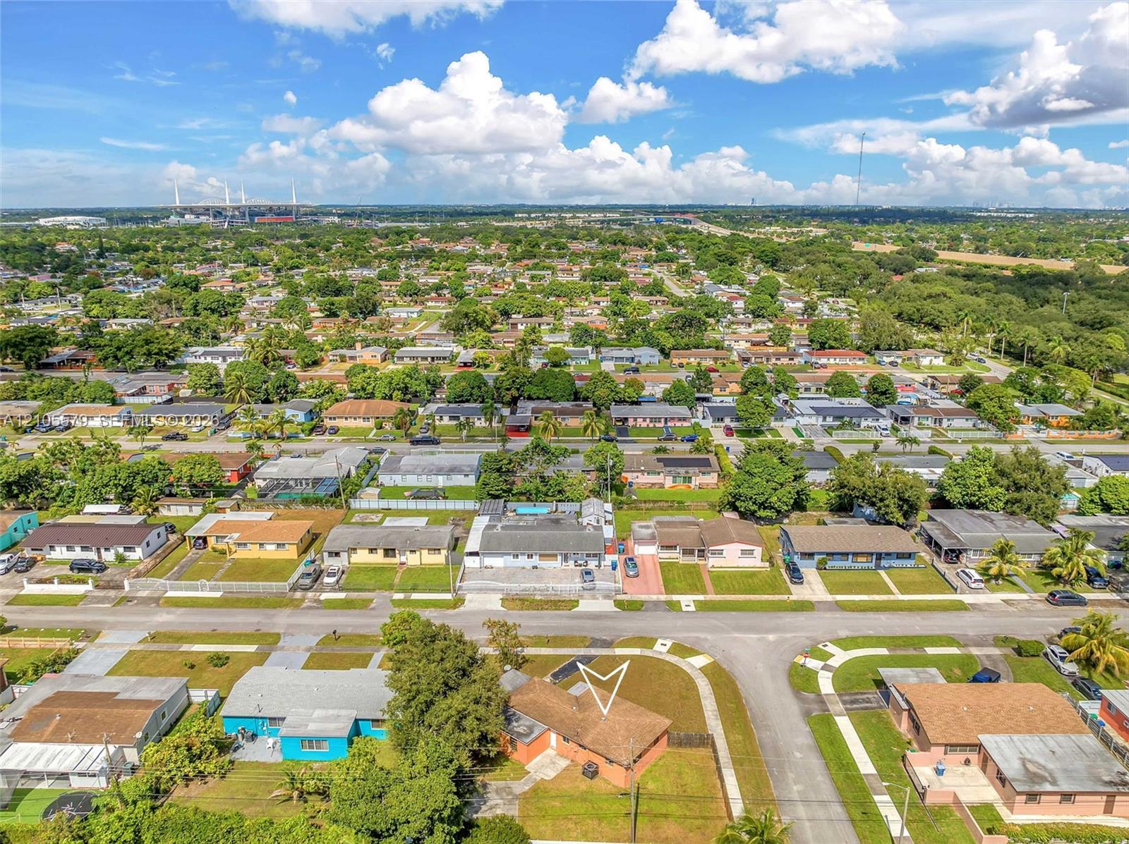 Aerial perspective of a residential property featuring a composition shingle roof, paved driveway, and established landscaping
