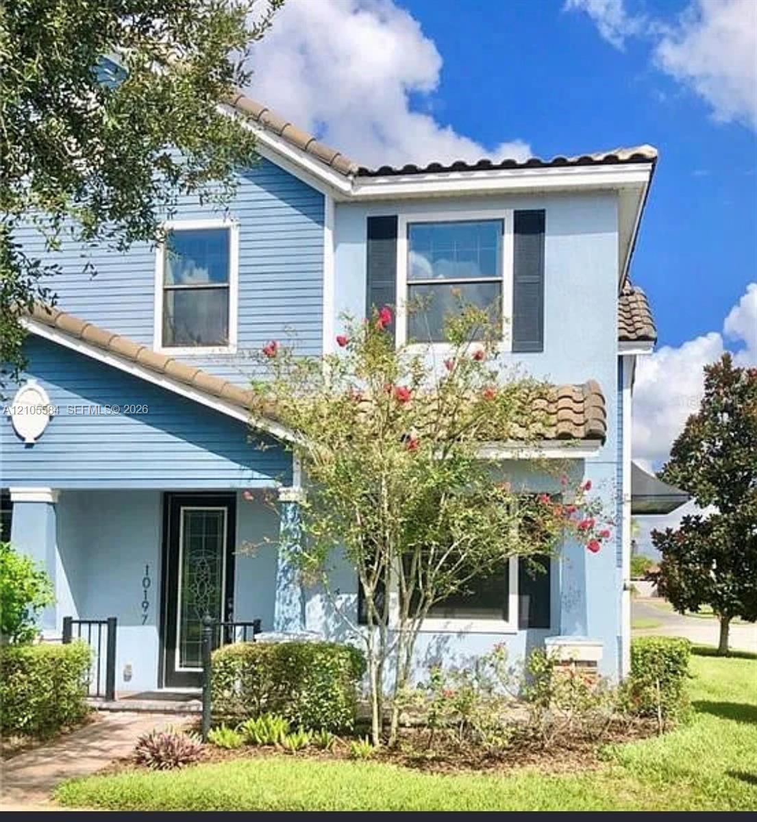 Two-story exterior featuring a mix of horizontal lap siding and smooth stucco finish, clay tile roof sections, decorative window shutters, and a glass-paneled entry door
