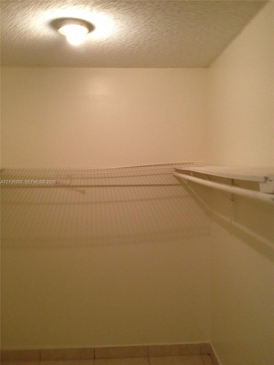Recessed lighting, textured ceiling, light-toned wall paint, wire shelving, tile flooring