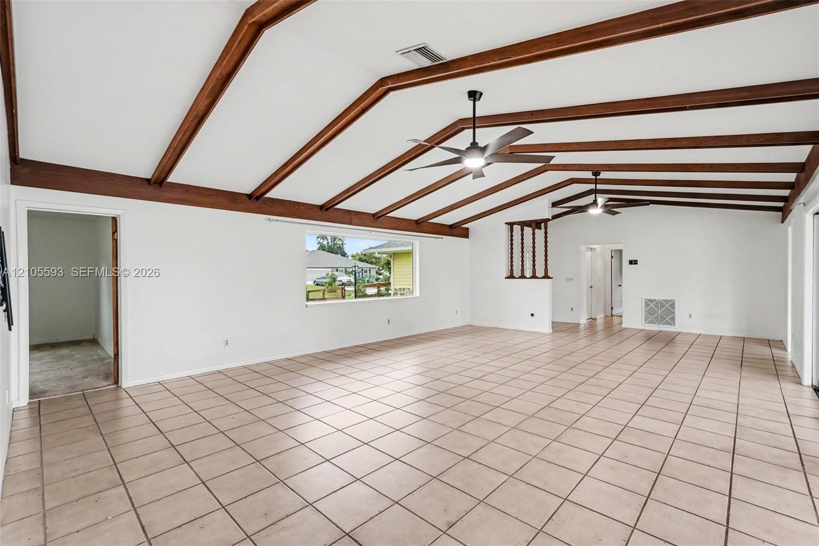 Vaulted ceilings featuring exposed wood beams, ceramic tile flooring, and dual ceiling fans