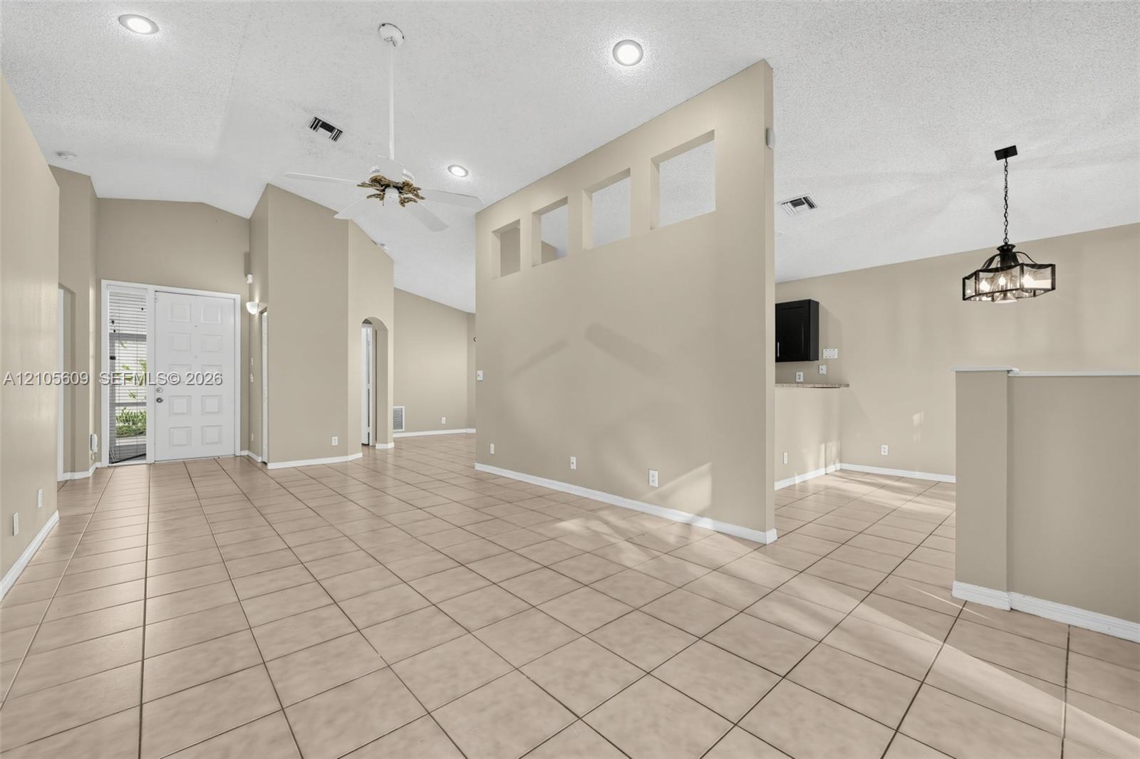 Ceramic tile flooring, vaulted ceilings with recessed lighting, interior partition wall with cutout architectural niches, and a multi-light pendant fixture Ceramic tile flooring, vaulted ceilings with recessed lighting, interior partition wall with cutout architectural niches, and a multi-light pendant fixture