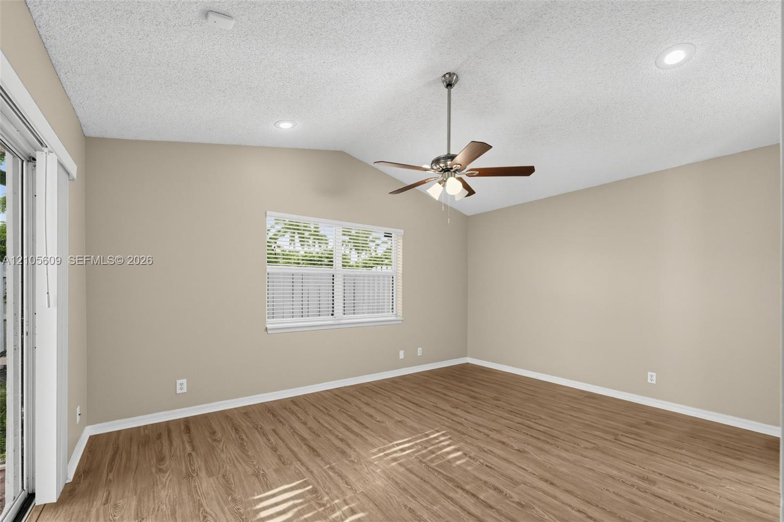 Vaulted ceilings, wood-finish flooring, recessed lighting, multi-blade ceiling fan with integrated light kit, and double-pane window with blinds