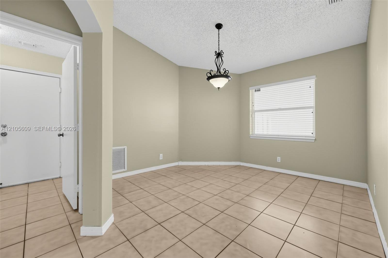 Neutral wall paint, tiled flooring, iron-finish pendant lighting, and horizontal window blinds Neutral wall paint, tiled flooring, iron-finish pendant lighting, and horizontal window blinds