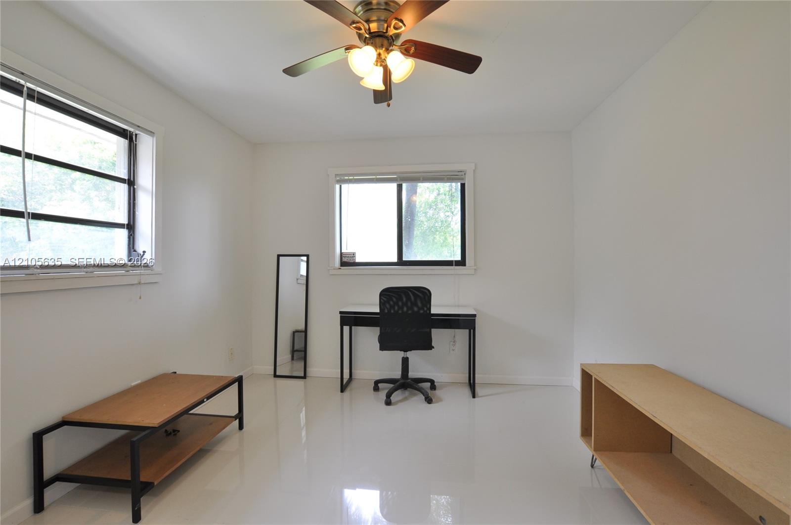 Interior room featuring neutral wall paint, polished finish flooring, dual sliding-sash windows, and a ceiling-mounted light fixture with a multi-blade fan