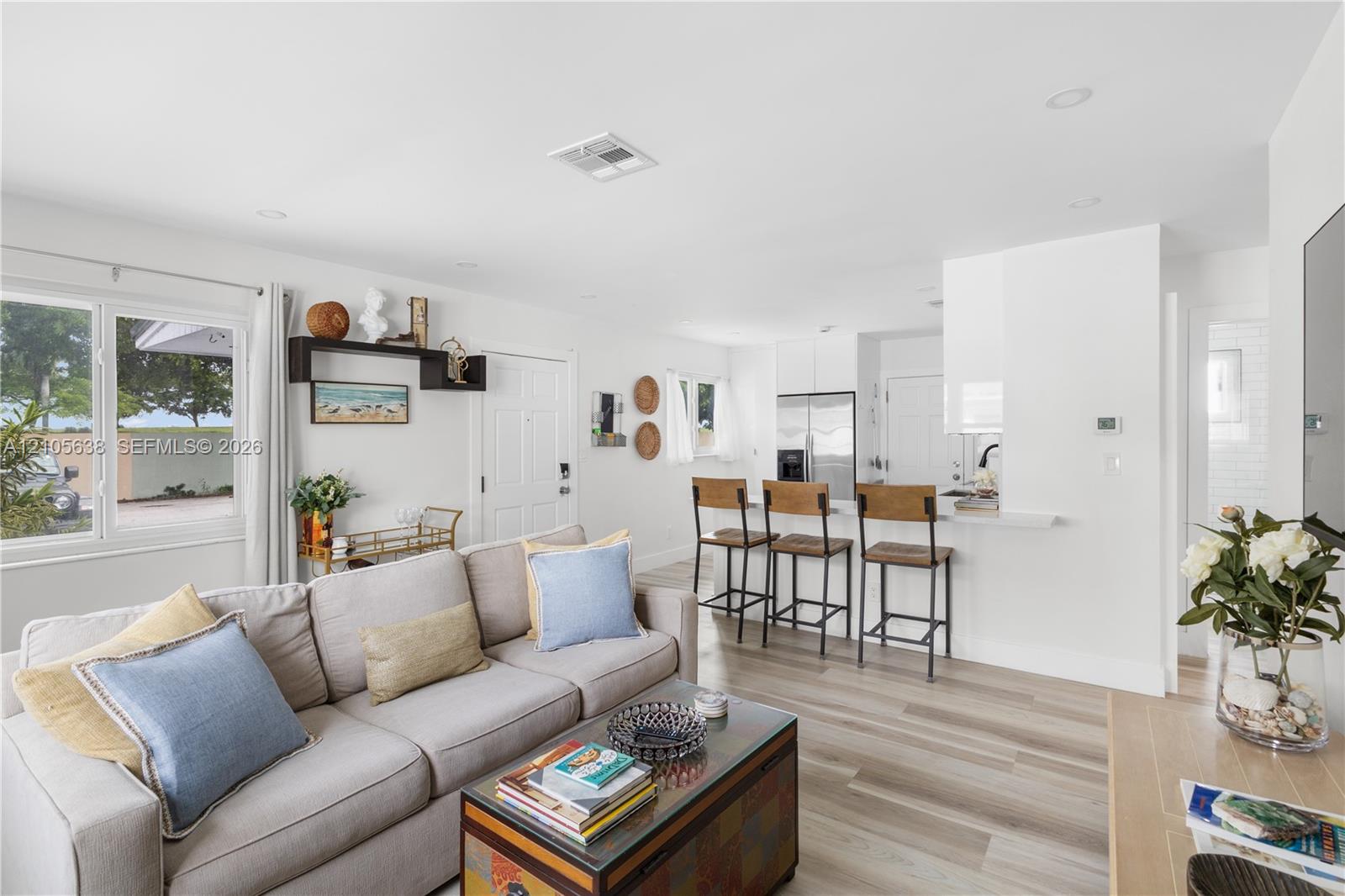 Open-concept living space featuring wood-finish flooring, recessed lighting, and a kitchen peninsula with breakfast bar seating