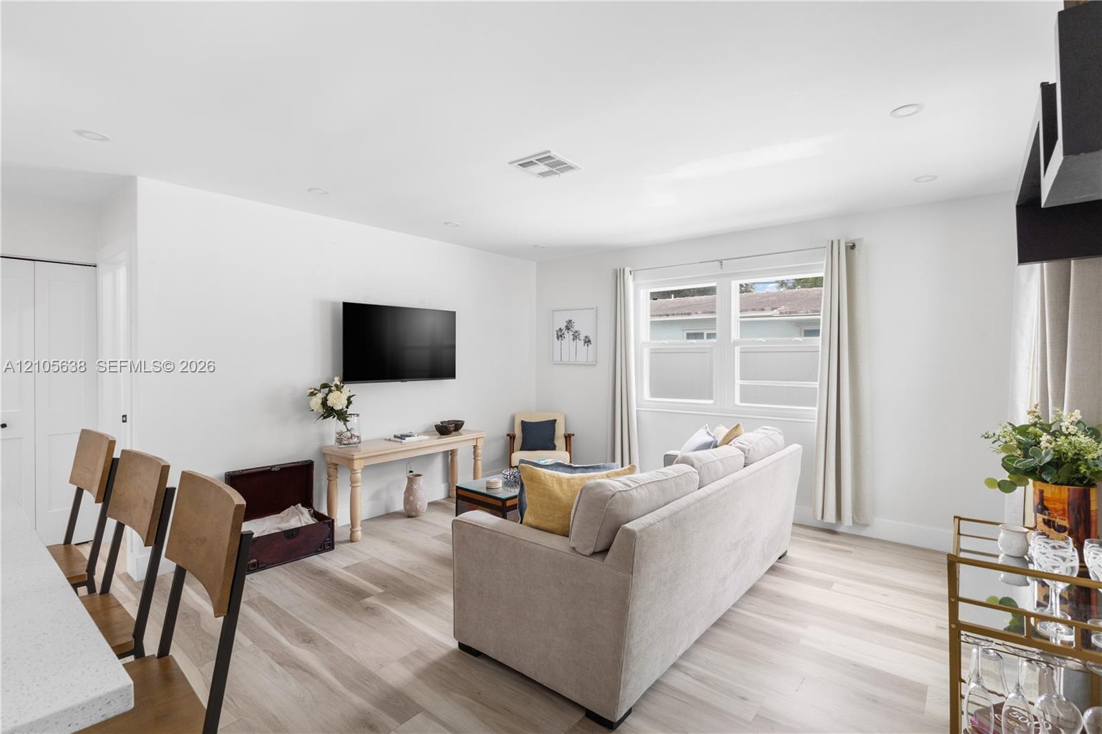 Open-concept interior featuring light wood-finish flooring, recessed lighting, and dual-pane windows