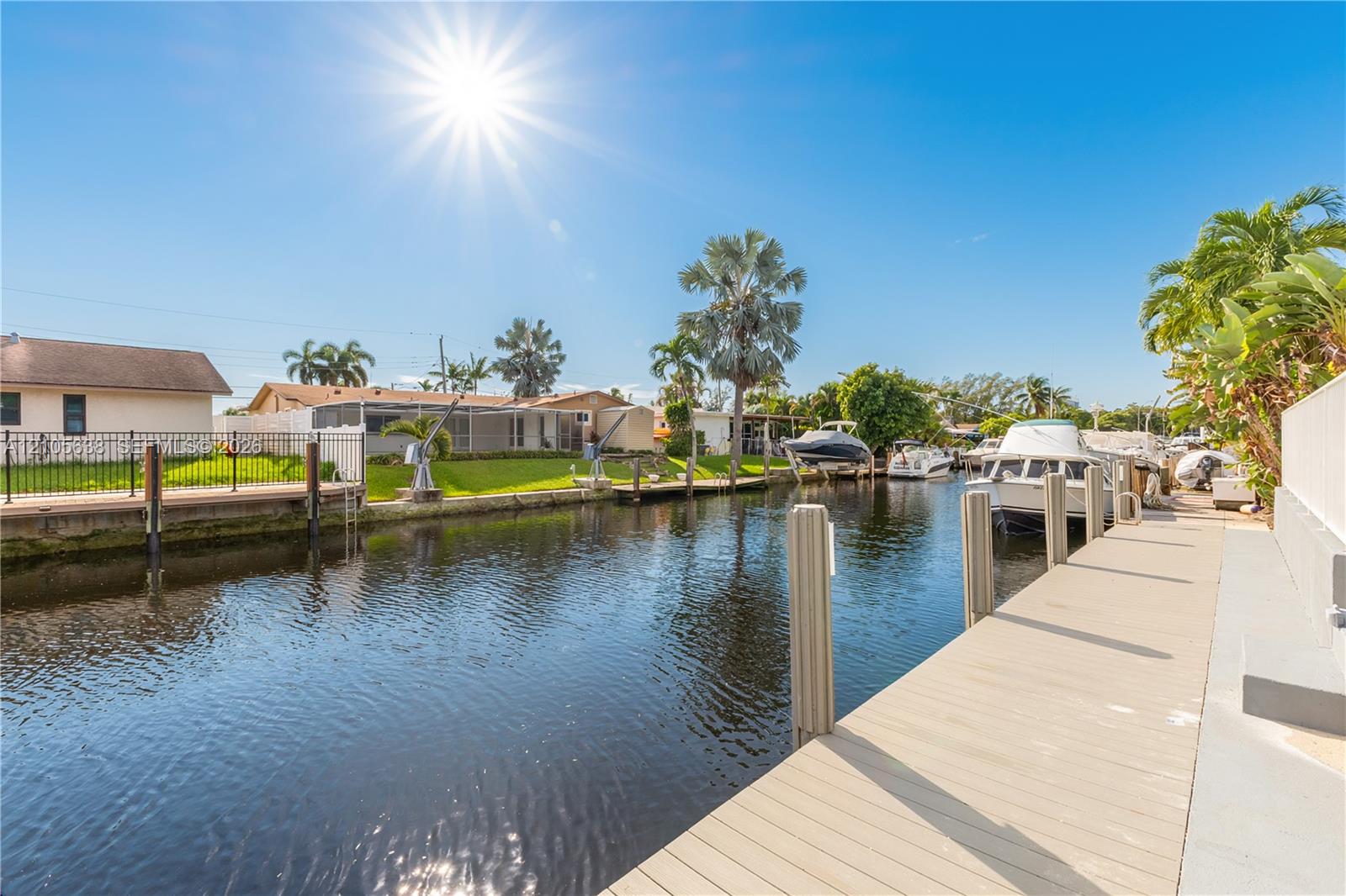 Waterfront property featuring a private canal-side dock, concrete bulkhead, and established palm trees