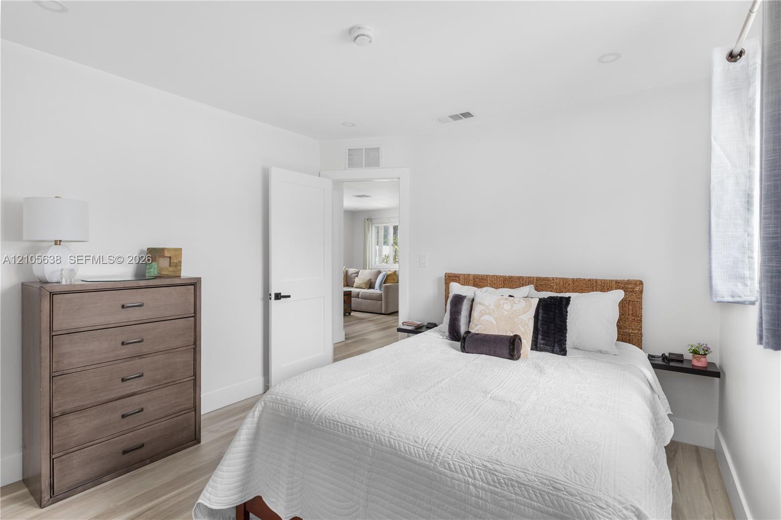 Neutral interior space featuring wood-finish flooring, recessed lighting, and a solid-core interior door with matte black hardware
