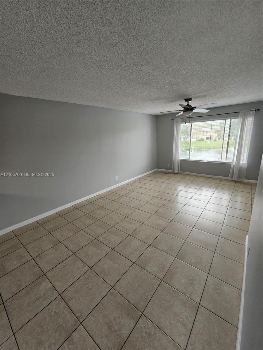 Interior room featuring large-format ceramic tile flooring, neutral wall paint, and a ceiling fan with integrated lighting