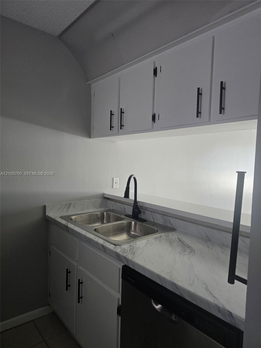 White cabinetry with matte black hardware, stone-finish countertops, stainless steel double-basin sink, and high-arc matte black faucet White cabinetry with matte black hardware, stone-finish countertops, stainless steel double-basin sink, and high-arc matte black faucet