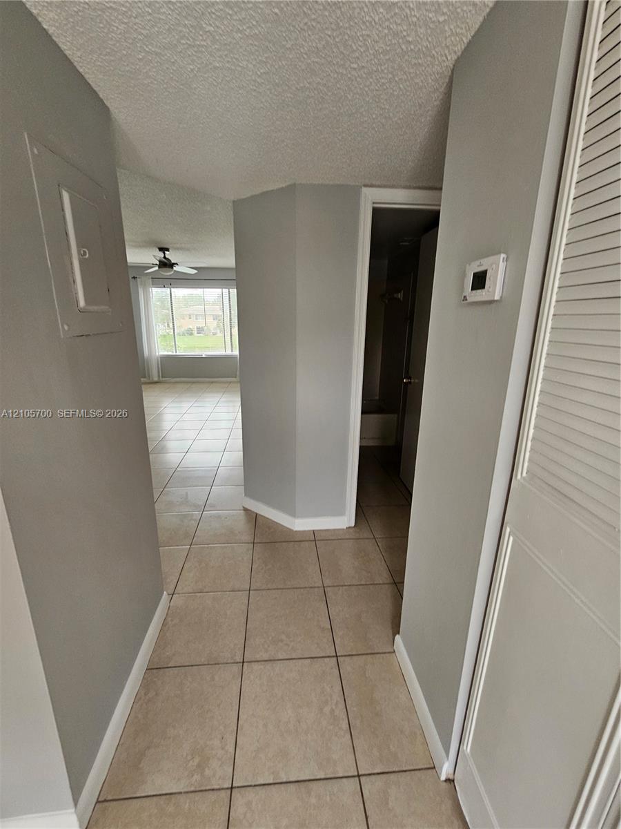 Ceramic tile flooring, louvered bi-fold closet doors, and wall-mounted digital thermostat