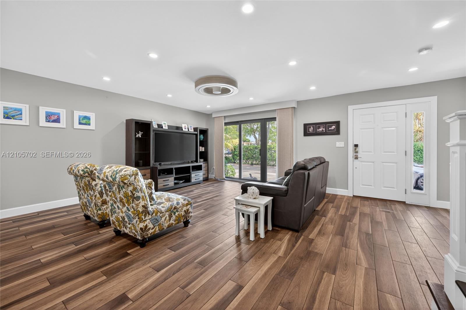 Open-concept interior featuring wood-finish flooring, recessed lighting, a modern ceiling fan, built-in shelving, and sliding glass doors