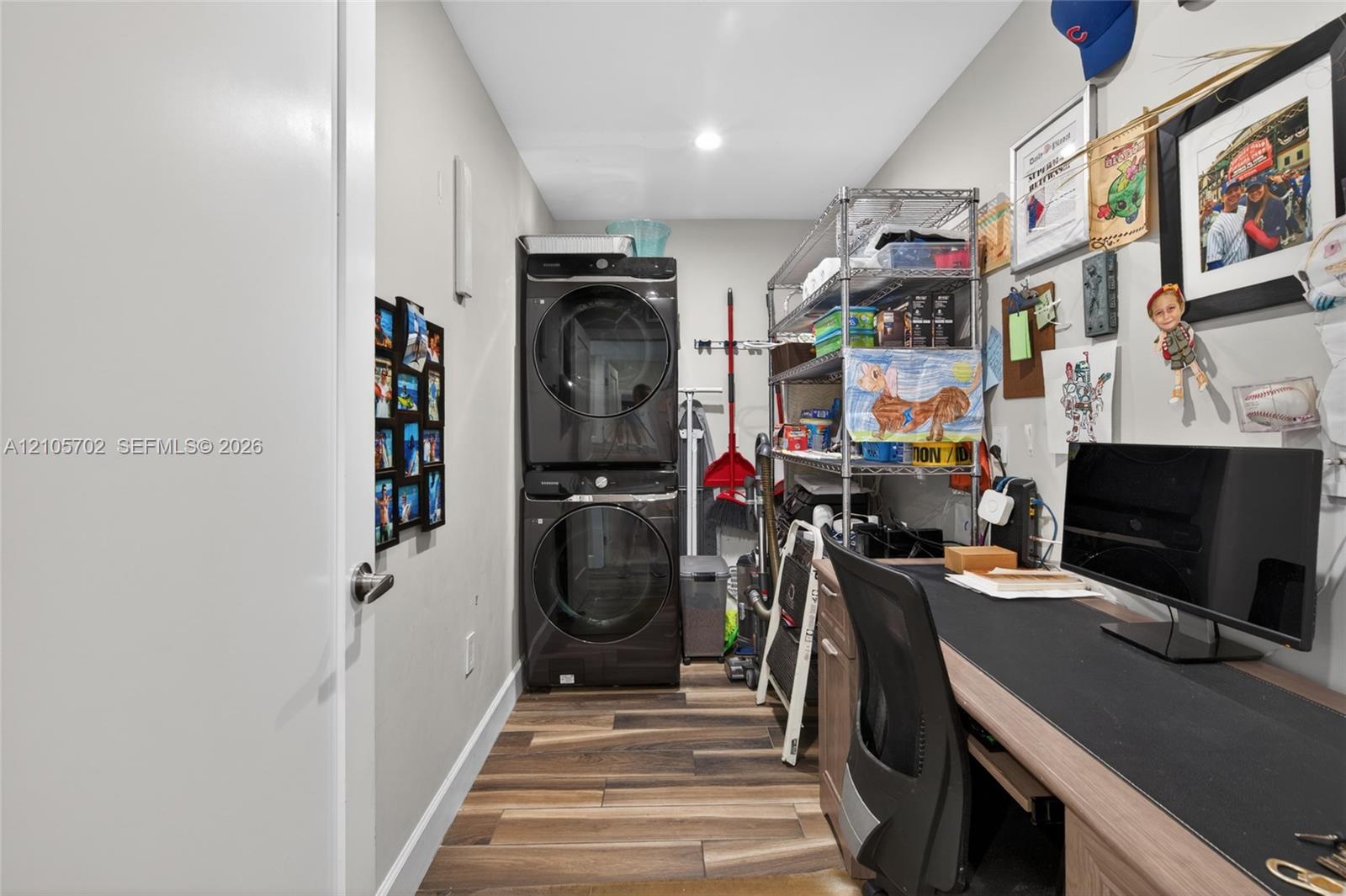 Dedicated utility area featuring stacked washer and dryer, wood-finish flooring, and built-in desk cabinetry