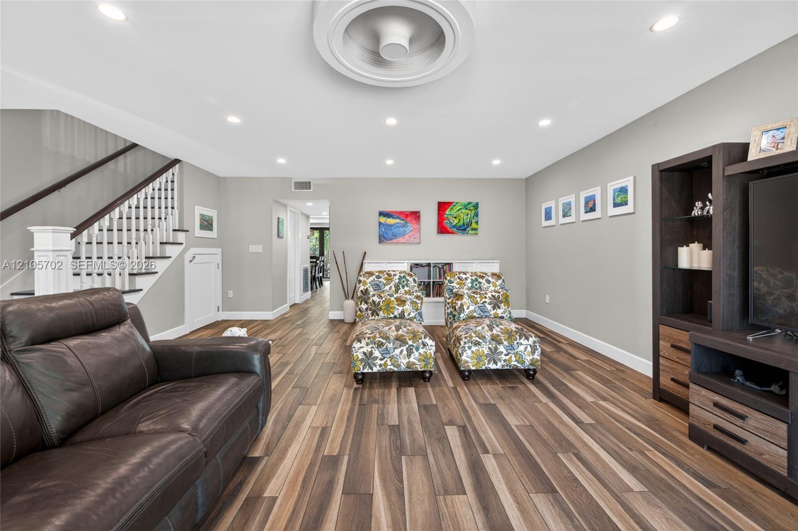 Interior space featuring wood-finish flooring, recessed lighting, a circular ceiling detail, and a wooden staircase with white balusters
